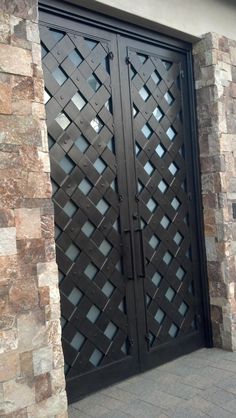 an iron gate is shown in front of a brick wall and stone pillars with glass inserts