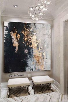 two white stools are in front of a large painting on the wall with gold paint