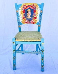 a blue chair with a fridace painted on the back and seat is against a white backdrop