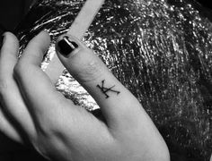 a woman's hand with a small tattoo on her left ring finger and an arrow in the middle