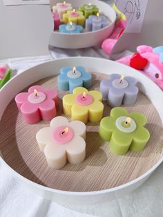 candles are arranged on a tray with flowers in the middle and small ones behind them