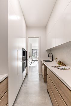 a long narrow kitchen with white walls and wooden cabinets