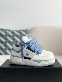 Embrace the spirit of rebellious luxury with these AMIRI MA-1-inspired sneakers in a crisp white and blue colorway. Crafted with a blend of premium leather and breathable mesh, these high-top sneakers capture the essence of AMIRI's signature aesthetic. The bold silhouette, featuring an exaggerated sole and signature details like the AMIRI logo on the side and tongue, exudes confidence and individuality. Experience the perfect fusion of comfort, quality, and head-turning style. Luxury High-top Custom Sneakers With Translucent Outsole, Luxury Custom High-top Sneakers With Translucent Outsole, Luxury Basketball Shoes, Luxury Lace-up Basketball Shoes, Luxury High-top Sneakers For Streetwear With White Sole, Luxury High-top Sneakers With White Sole For Streetwear, Modern Custom Blue Sneakers, Luxury White High-top Sneakers With Laces, Designer High-top Custom Sneakers With Translucent Outsole