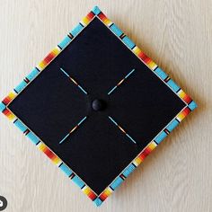 a black square with blue, red, yellow and orange squares on it sitting on top of a wooden table