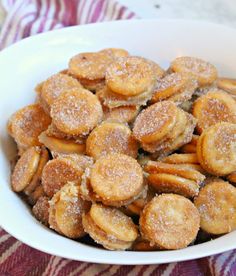 a white bowl filled with powdered sugar covered donuts on top of a table