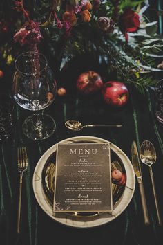 an elegant table setting with menu and silverware, apples and flowers in the background