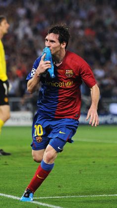 a soccer player is running with the ball in his hand and holding a water bottle