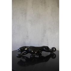 a black cat figurine sitting on top of a table next to a wall