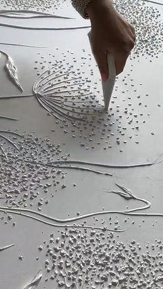 someone is drawing something on the ground with white paint and water drops all over it