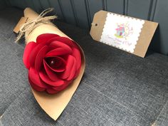 a red flower is sitting on top of a piece of cardboard