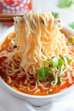 a bowl of noodles with chopsticks sticking out of the top, on a white plate