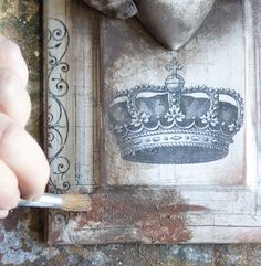 a person is using a brush to paint the crown on a piece of wood that has been painted