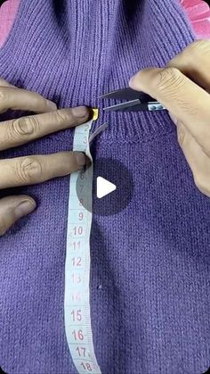 a woman is measuring her waist with a pair of scissors while wearing a purple sweater