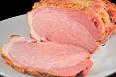 sliced ham on a white plate sitting on a wooden table