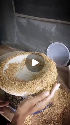 a person is holding a bowl with food in it and making something out of wood shavings