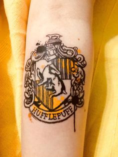 a person with a harry potter tattoo on their arm and the hogwarts crest