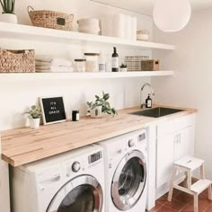 a washer and dryer in a small room with shelves above the washer