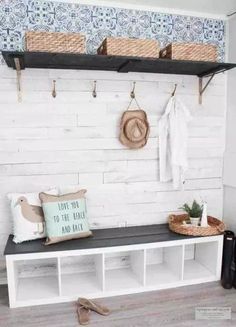 a bench with some baskets on it and two coats hanging from the hooks above it