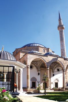 an old building with a large blue dome on it's roof and some flowers in the foreground