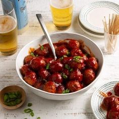 a white bowl filled with meatballs next to two glasses of beer and chopsticks