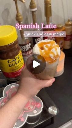 a person holding up a small cup filled with ice cream and caramel in front of some condiments