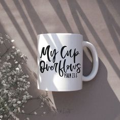 a coffee mug with the words my cup is overflowing on it next to some flowers