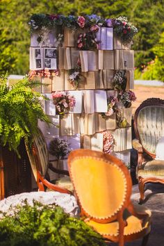 an old chair and some chairs with flowers on them in front of a wall made out of books