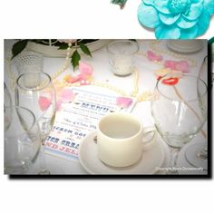 a table topped with glasses and plates covered in frosted glass next to a blue flower