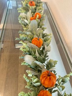 a glass table topped with orange flowers and greenery