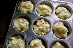 a muffin tin filled with cupcakes on top of a wooden table