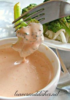 broccoli is being dipped with sauce in a bowl