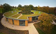 an aerial view of a circular building with grass on the roof