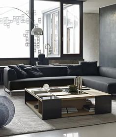 a living room filled with black furniture and large windows in front of the couches