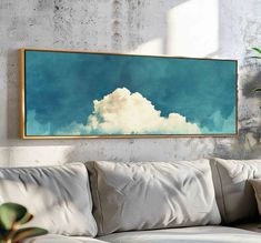 a painting hanging on the wall above a couch in a living room with white pillows