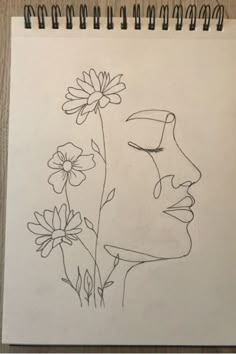 a drawing of a woman's face next to flowers