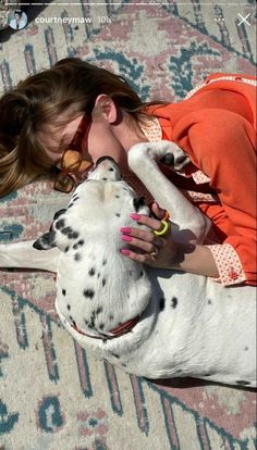 a woman laying on top of a rug next to a dalmatian