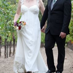 a bride and groom are walking through the vineyard