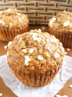 three muffins sitting on top of a table with white paper and nuts in the middle