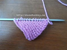 a crocheted triangle is sitting on a table next to a knitting needle and thread