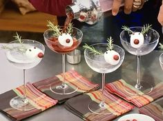 several martini glasses with olives and garnishes in them