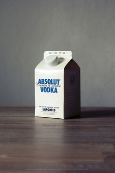 a carton of absolut vodka sitting on a wooden table in front of a gray wall