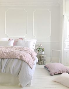 a bedroom with white walls and pink linens on the bed, along with pillows