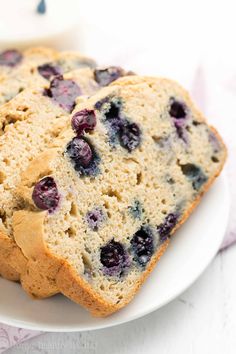 two slices of blueberry bread on a plate with a glass of milk in the background