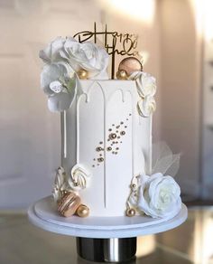 a white and gold wedding cake with flowers on top