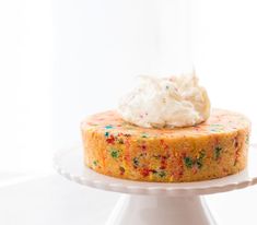 a cake with white frosting and sprinkles on top sitting on a plate