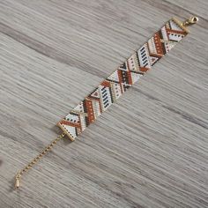 a bracelet that is sitting on top of a wooden table with a chain attached to it