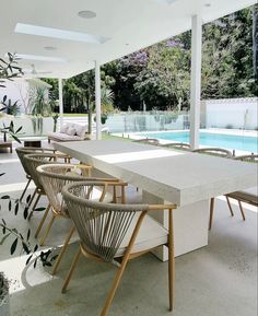 an outdoor dining area with chairs, table and pool in the backround behind it