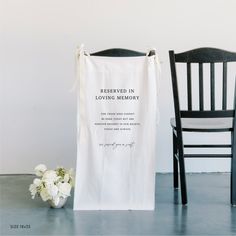 a white towel sitting on top of a wooden chair next to a vase with flowers