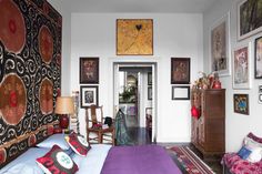 a bedroom with pictures on the wall and a purple bed in front of a doorway