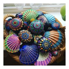 a basket filled with lots of different colored seashells on top of a window sill